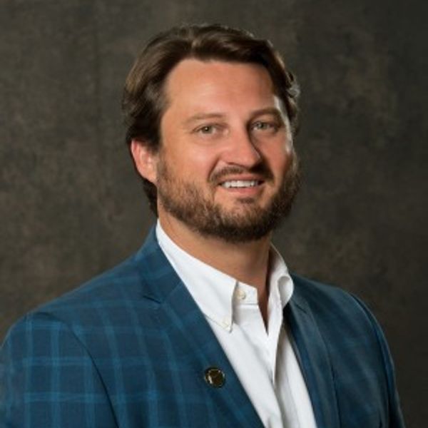 Man wearing a blue checked blazer and white shirt.
