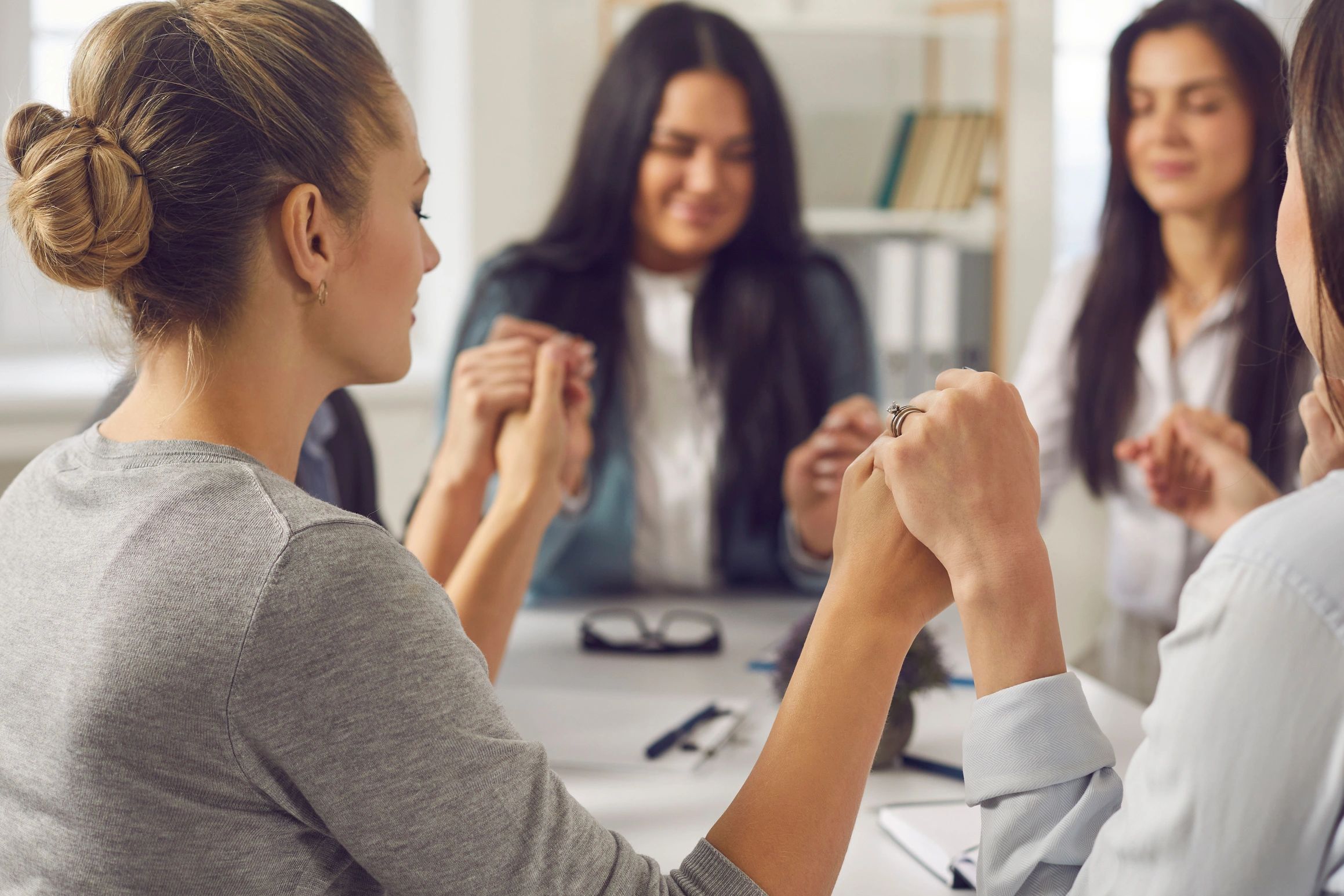 Group of women holding hands in support circle.