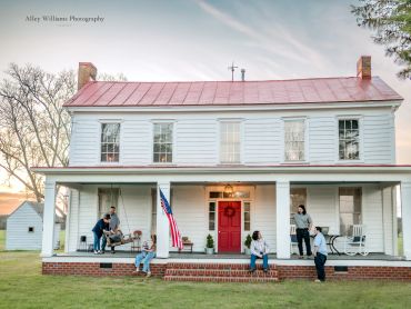 Family gathered on the front porch of historic Sunbury Farmhouse in Gates County, NC.