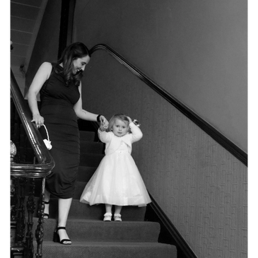 Nanny walking down stairs with flower girl at wedding
