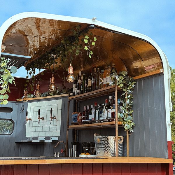 Cozy outdoor bar setup with hanging lights and greenery.