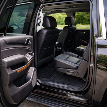Open rear door showing black leather interior of a Chevrolet Suburban.
