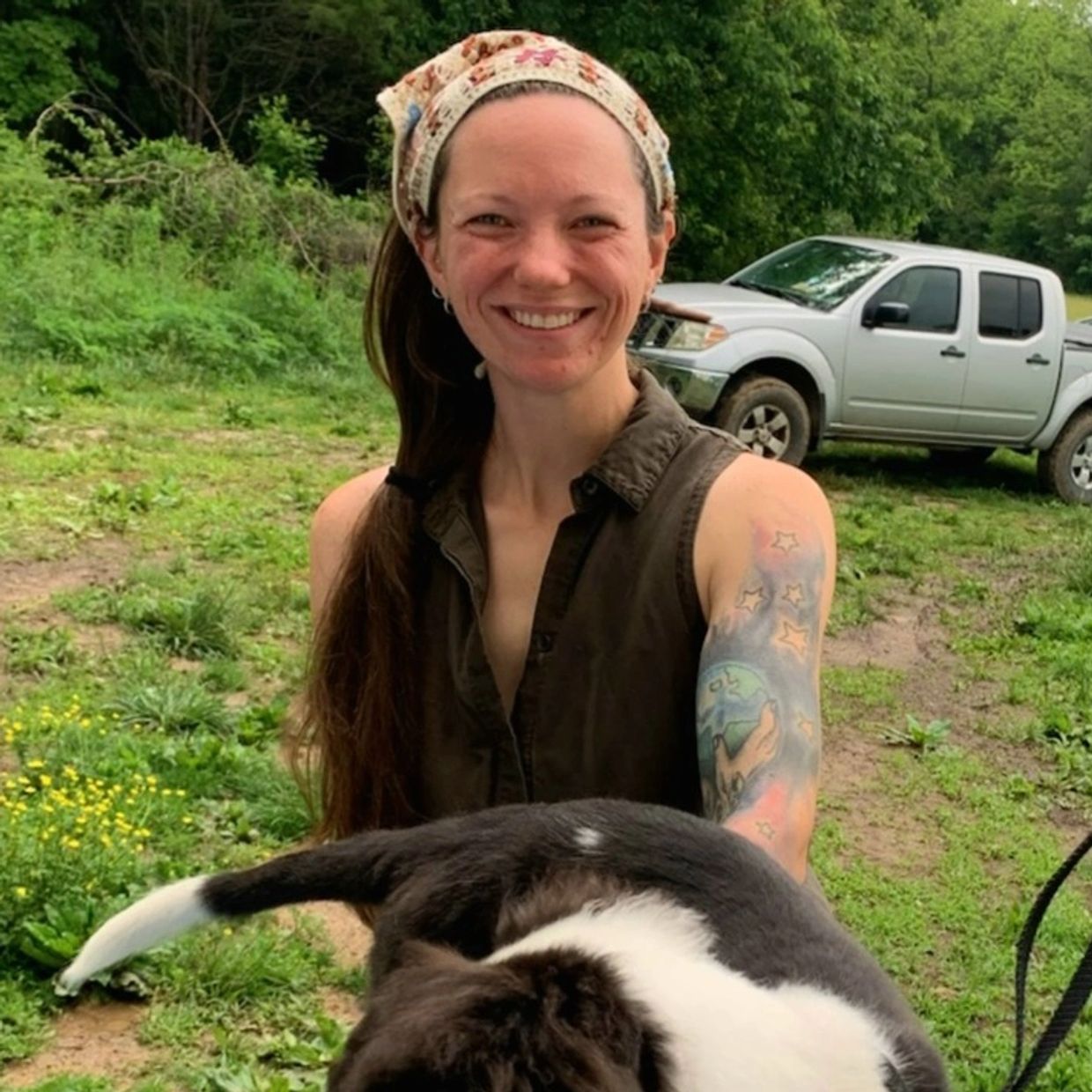 Smiling woman with a floral headband holding a black-and-white dog.