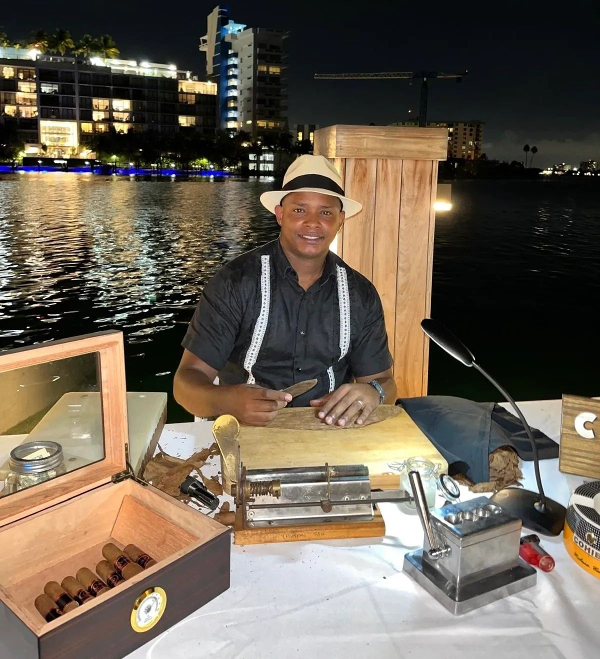 Man rolling cigars at night by the water.