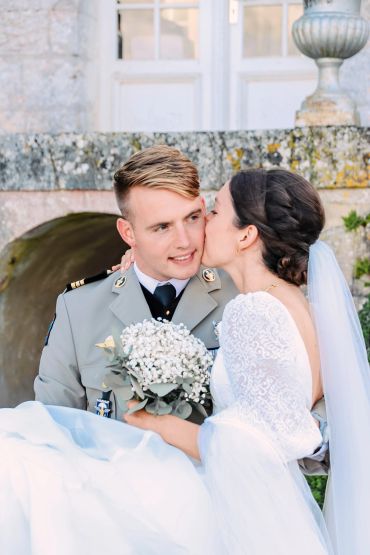 Mariée embrassant son mari en uniforme militaire.