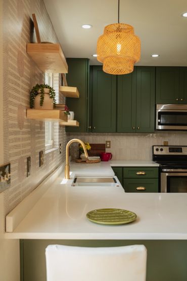 Modern kitchen with green cabinets, white countertops, and a woven pendant light.
