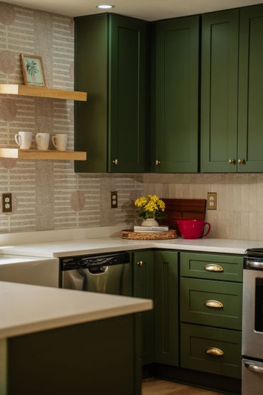 Cozy kitchen with dark green cabinets and white countertops.