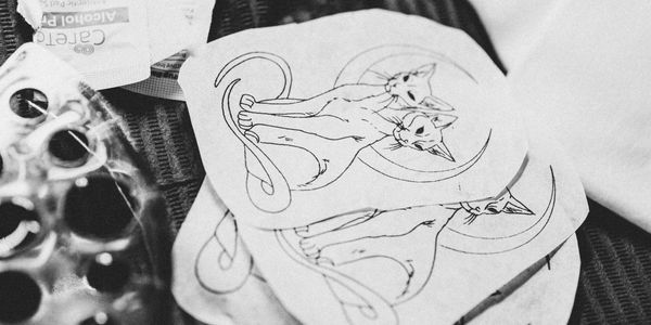 Stack of hand-drawn cat sketches on paper, black and white photo.
