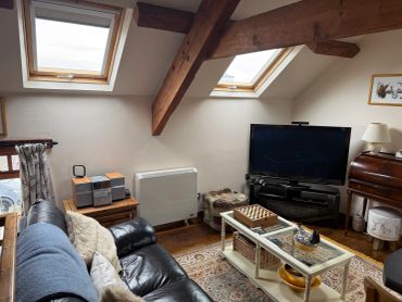 Cozy living room with slanted windows and wooden beams.