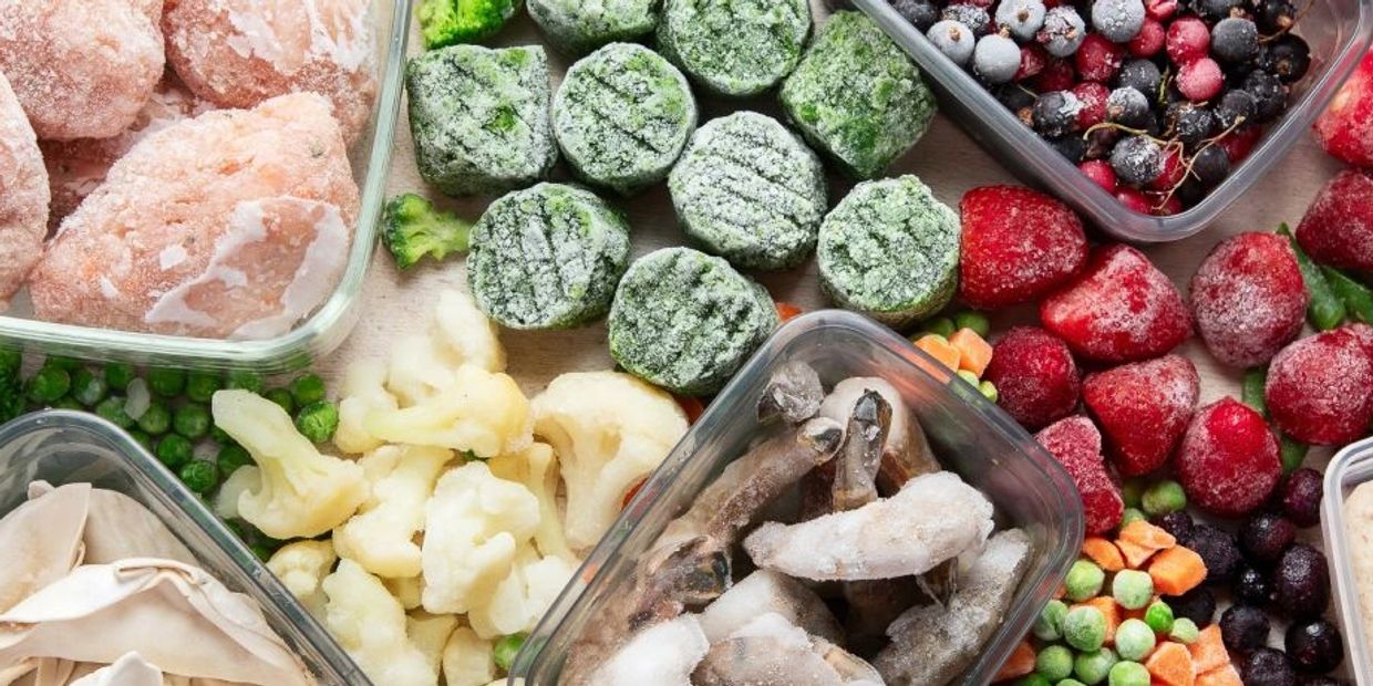 Variety of frozen vegetables and fruits in containers.