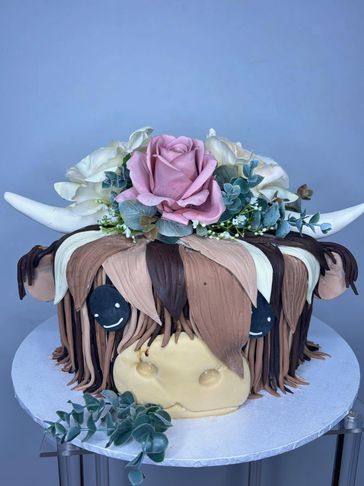 A whimsical cake decorated with horns, flowers, and drips resembling hair.