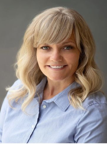 Smiling woman with blonde hair in a blue shirt.