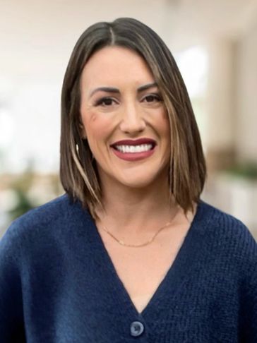 Smiling woman with straight shoulder-length hair in a blue sweater.