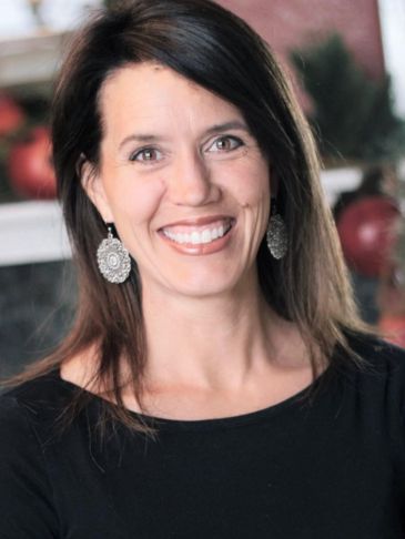 Smiling woman with long dark hair and earrings.