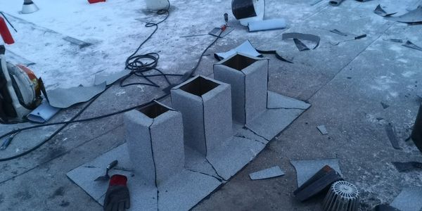 Three chimney bases under construction on a rooftop with tools scattered around.