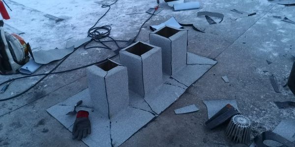 Three chimney bases under construction on a rooftop with tools scattered around.