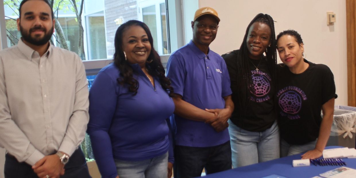 Group of five people smiling and posing indoors.