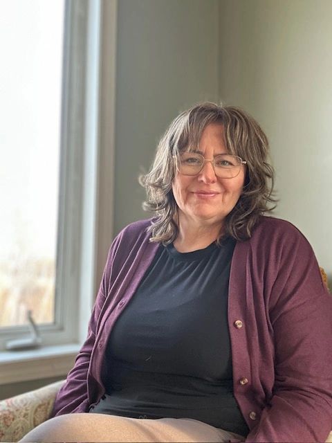 Woman smiling while sitting by a window.