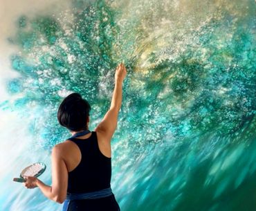 Artist painting a vibrant nature-inspired mural with green and blue hues.
