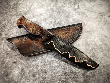 Decorative knife with a patterned blade and leather sheaths.