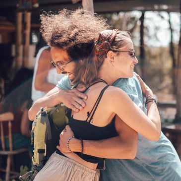 Two friends warmly embracing outdoors in casual attire.