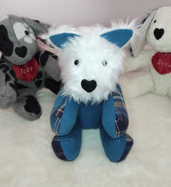 Three stuffed dogs with heart-shaped noses and personalized red heart tags.