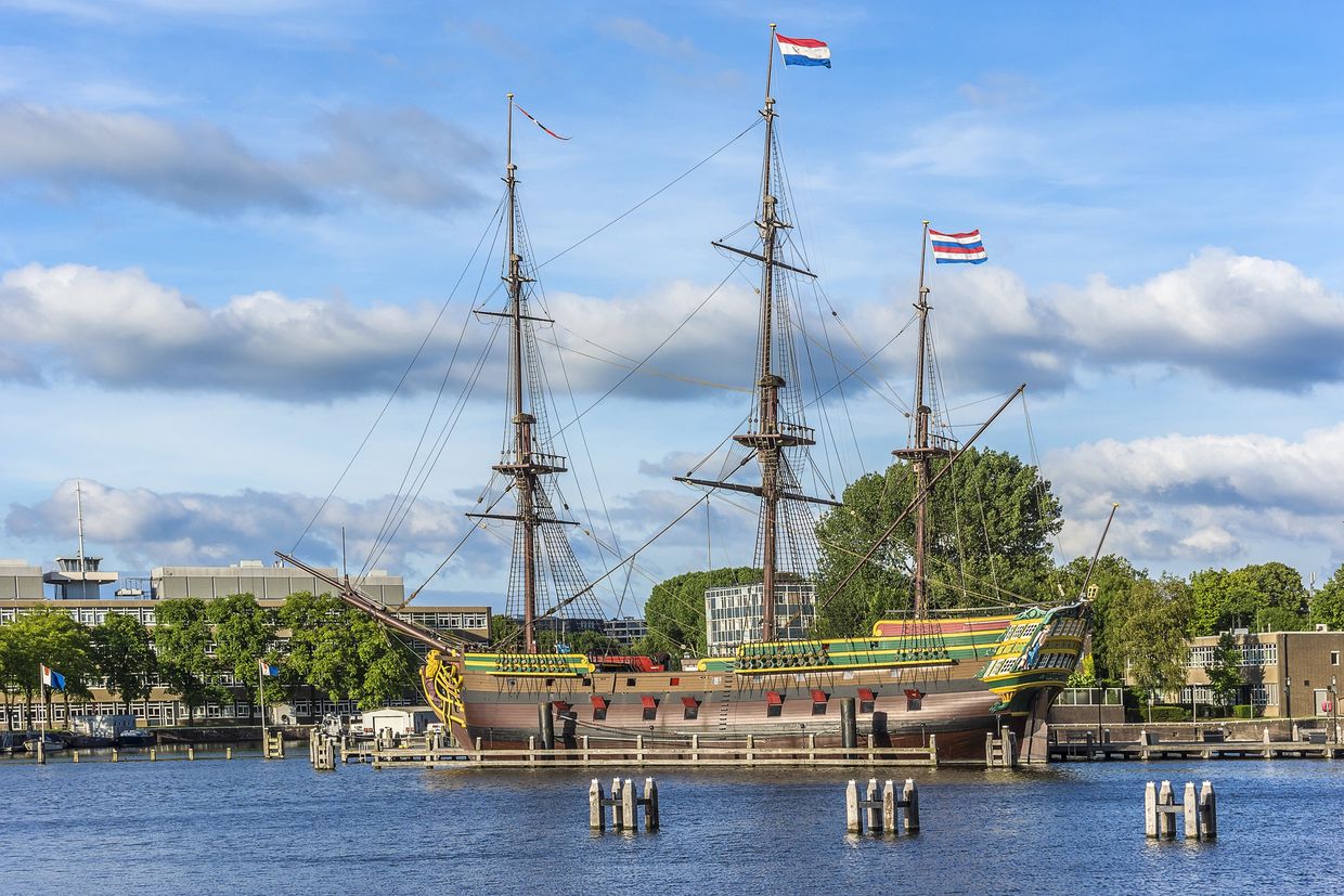 Historic Dutch ship docked by the waterfront under a clear sky.