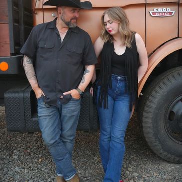 Man and woman leaning against a vintage Ford truck.