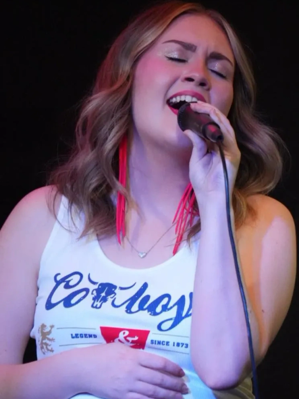 Young woman passionately singing into a microphone.