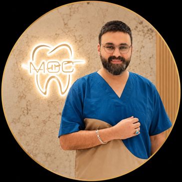 Dentist in blue scrubs standing in a clinic.