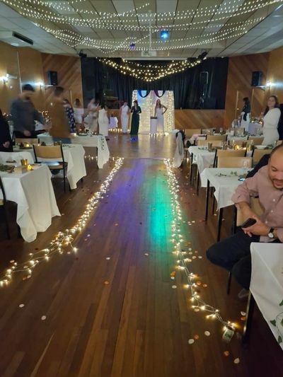 Decorated indoor event space with string lights and tables arranged for guests.