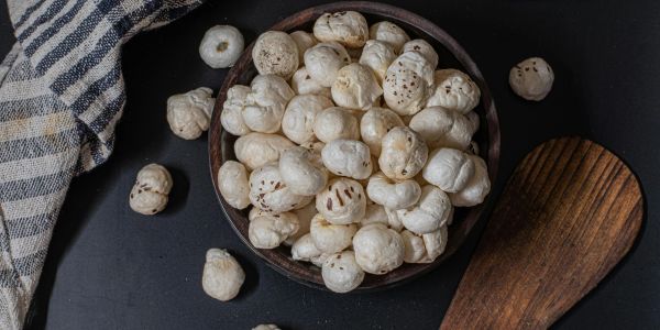 Bowl of puffed lotus seeds on a black surface.