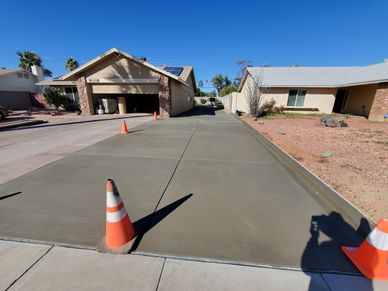 Freshly poured concrete driveway with safety cones on a sunny day.