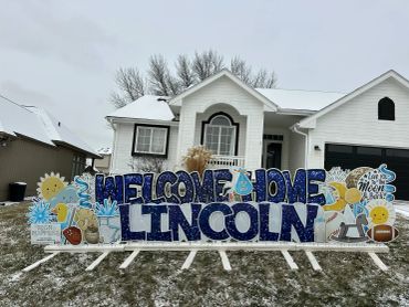 Yard sign saying welcome home Lincoln in front of a house.