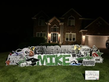 Yard sign congratulating Mike on his graduation in front of a house at night.