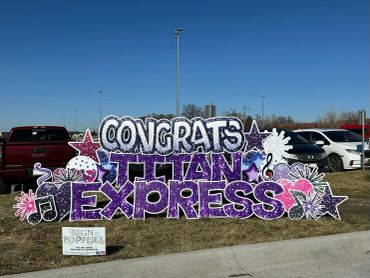 Colorful Congrats Titan Express yard sign in a parking lot.