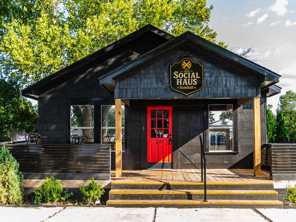 Black building with a bright red door and a sign reading Social Haus Tomball.