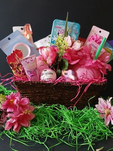 Decorative gift basket with pink flowers and assorted items.