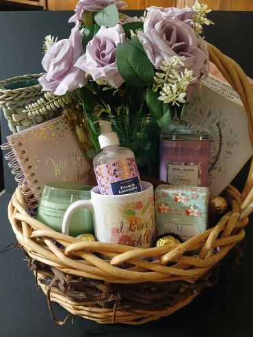 Gift basket with flowers, candles, lotion, and a mug.