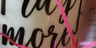 Close-up of a mug with text and pink decorative ribbons.