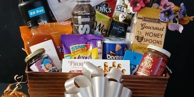 Gift basket filled with snacks and honey spoons.