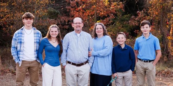 A family of six posing outdoors in fall.