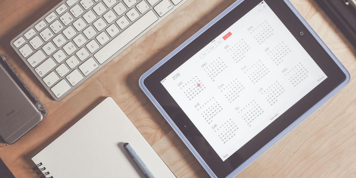 A keyboard with a phone, calendar, and notepad for a meeting.