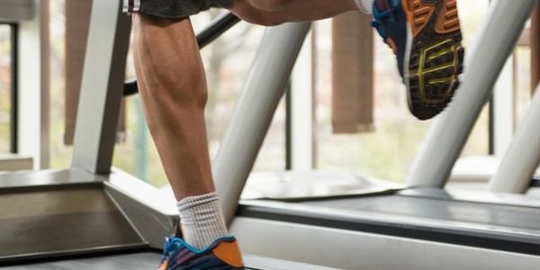 Close-up of a person running on a treadmill wearing athletic shoes.