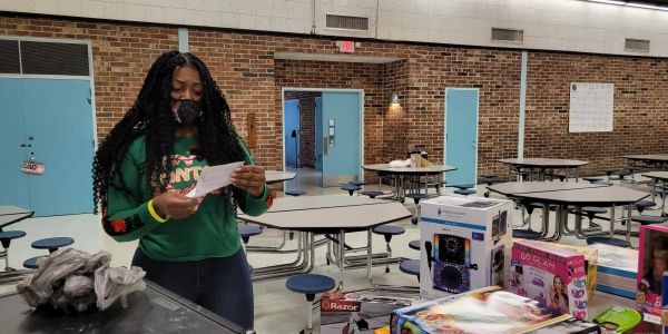 A woman reads a paper in a room with tables and assorted boxed items.