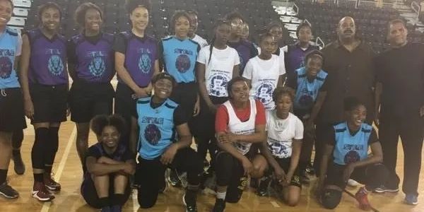 A group photo of a girls' basketball team in a gym.