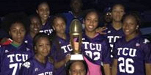 Youth football team posing with a trophy at night.