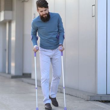 Man walking with crutches outdoors.