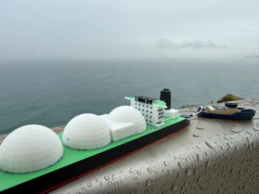 Model ship with ocean backdrop on wet surface.