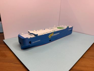 Model of a blue and white cargo ship on a flat surface.
